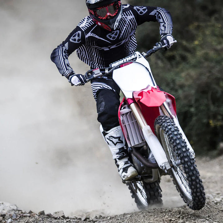 Michelin MX tyres on an MX motorbike, racing towards the camera with rider standing on pegs.